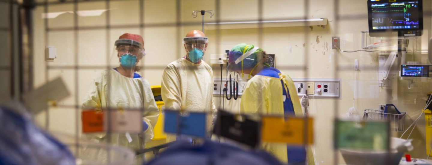 Healthcare workers wearing medical masks are seen through a window