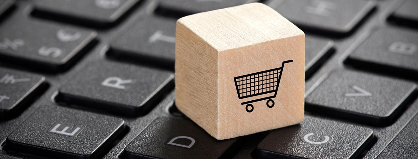 Wooden block with shopping cart graphic on laptop keyboard.