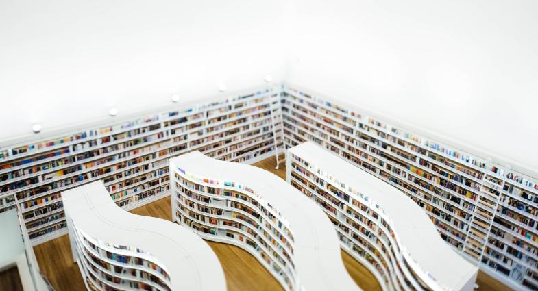 An arial view of a bookstore with curved, white bookshelves full of books.