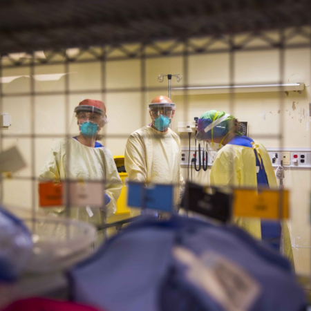 Healthcare workers wearing medical masks are seen through a window