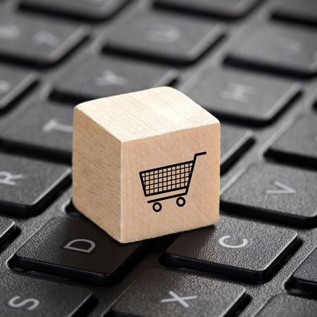 Wooden block with shopping cart graphic on laptop keyboard.